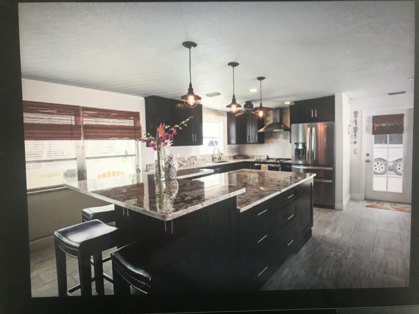 Modern kitchen with dark cabinetry, granite countertops, and pendant lighting.