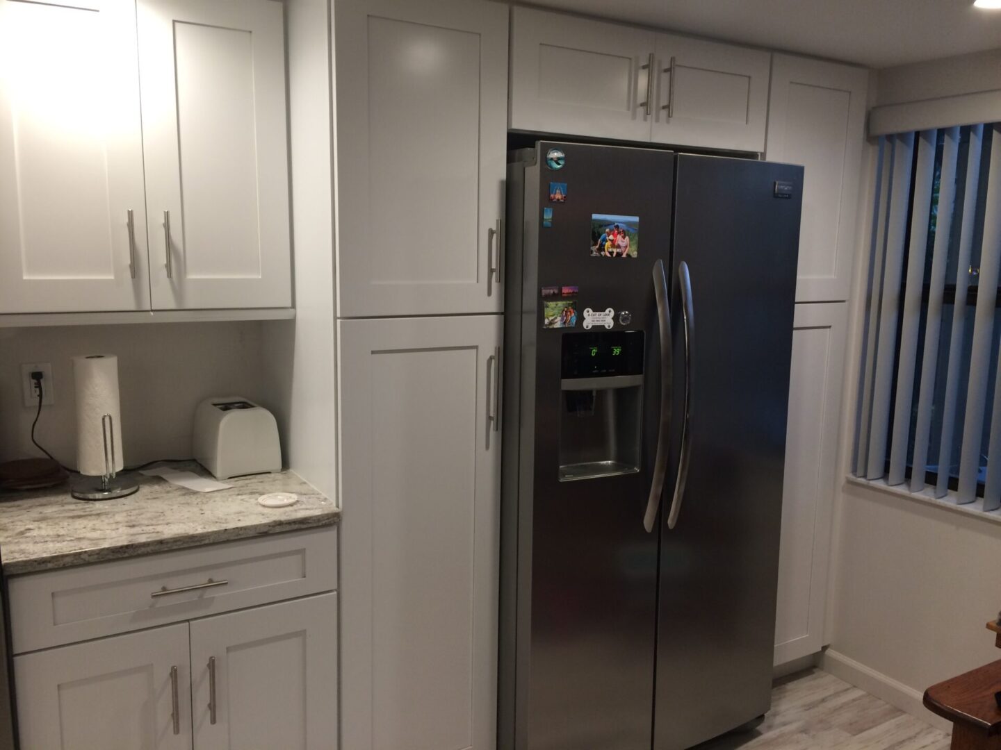 Modern kitchen with stainless steel refrigerator and white cabinetry.