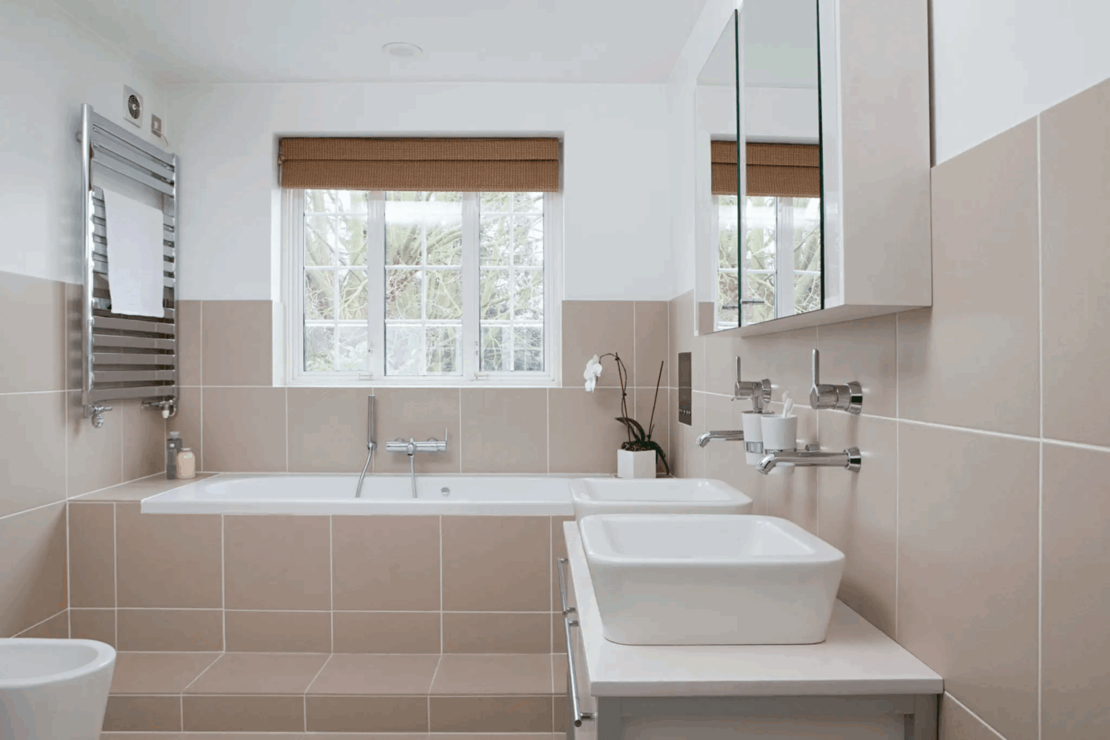 Modern bathroom with a bathtub and sink under a large window.